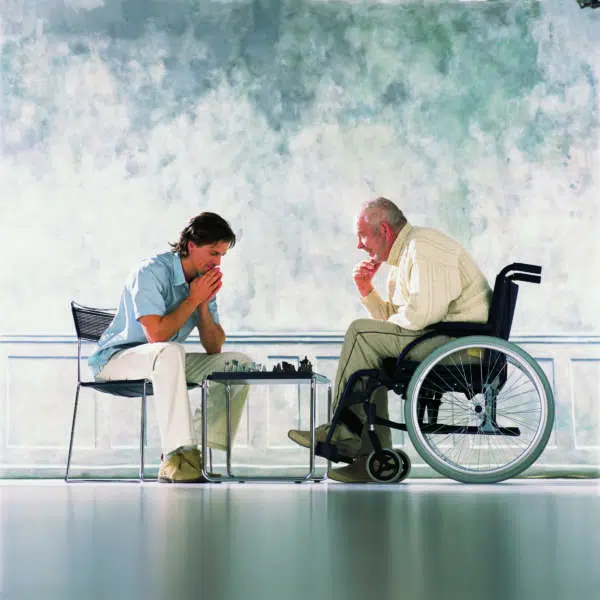 Person in Rollstuhl sitzt am Tisch